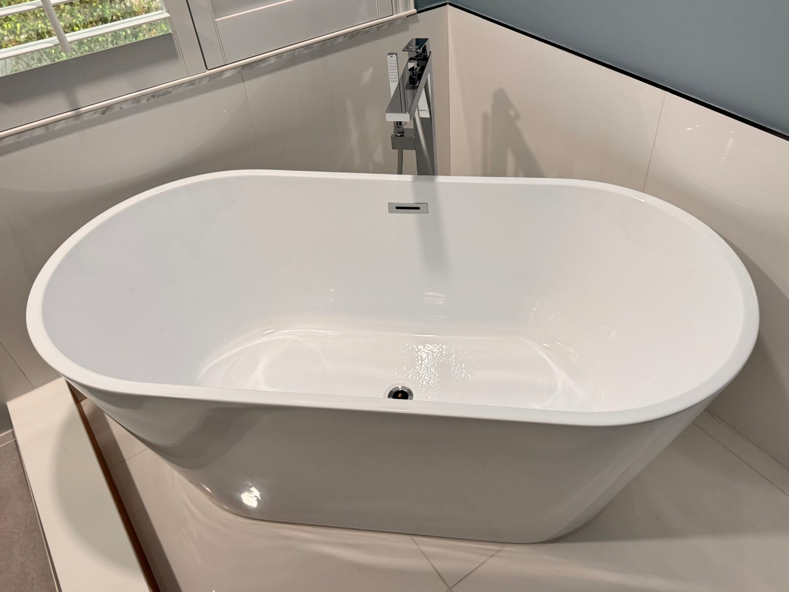 Clean freestanding bathtub after refinishing, centered in the finished bathroom