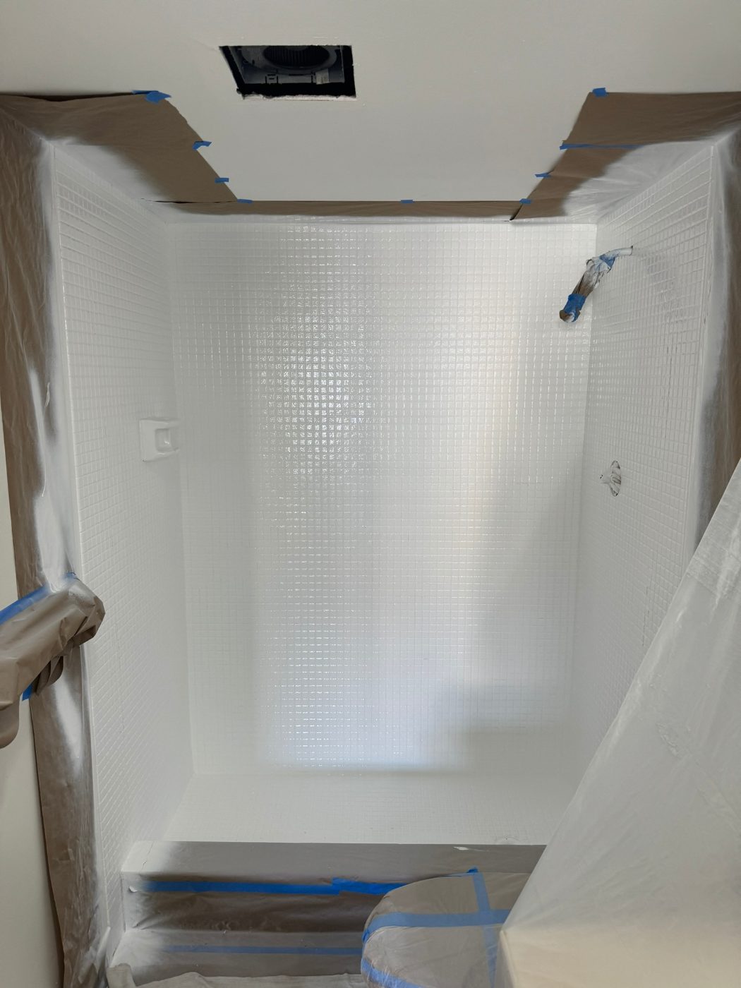 The same mosaic-tile stall refinished in uniform bright white