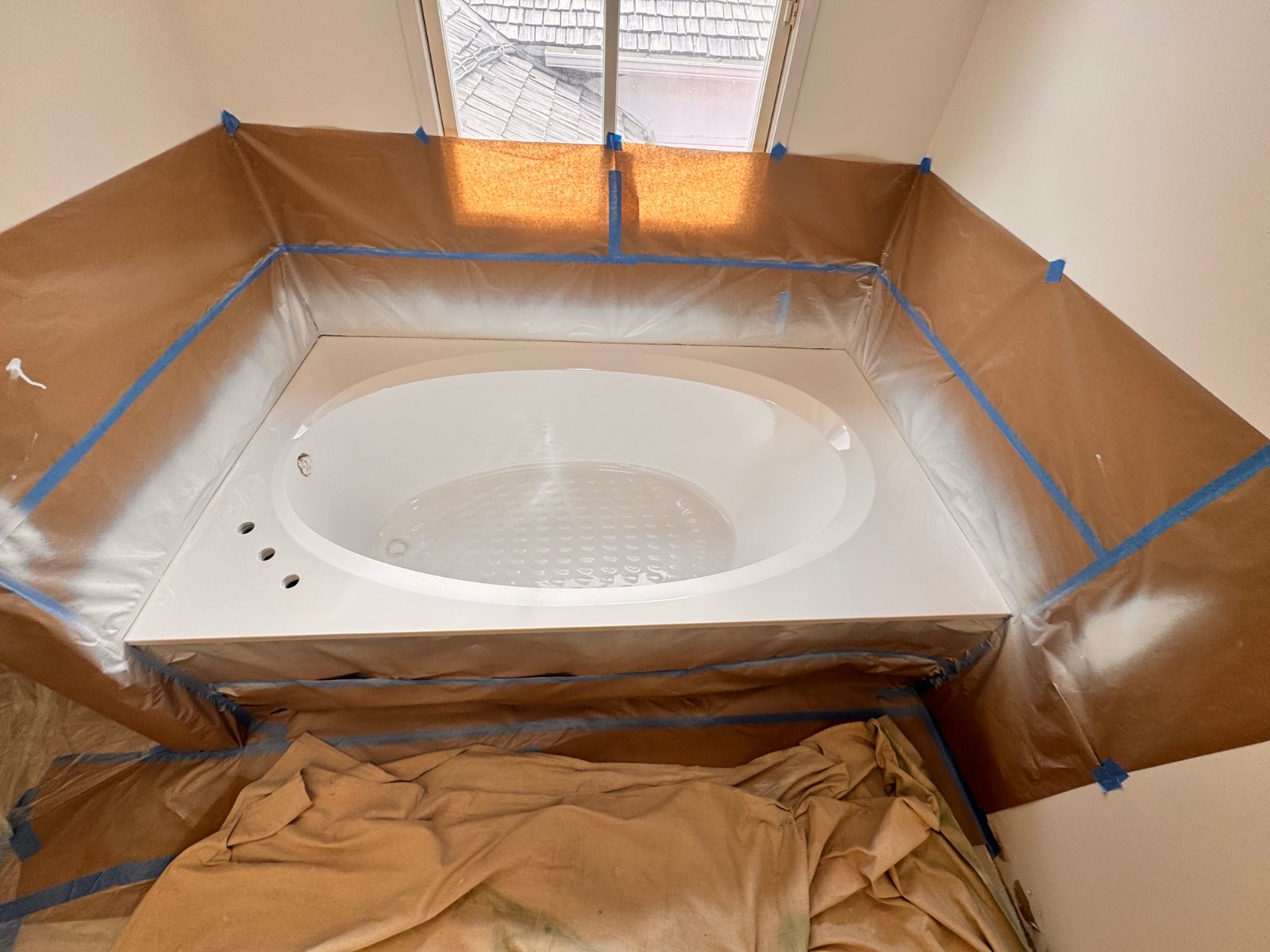 A garden drop-in spa freshly sprayed white, the room still masked around it