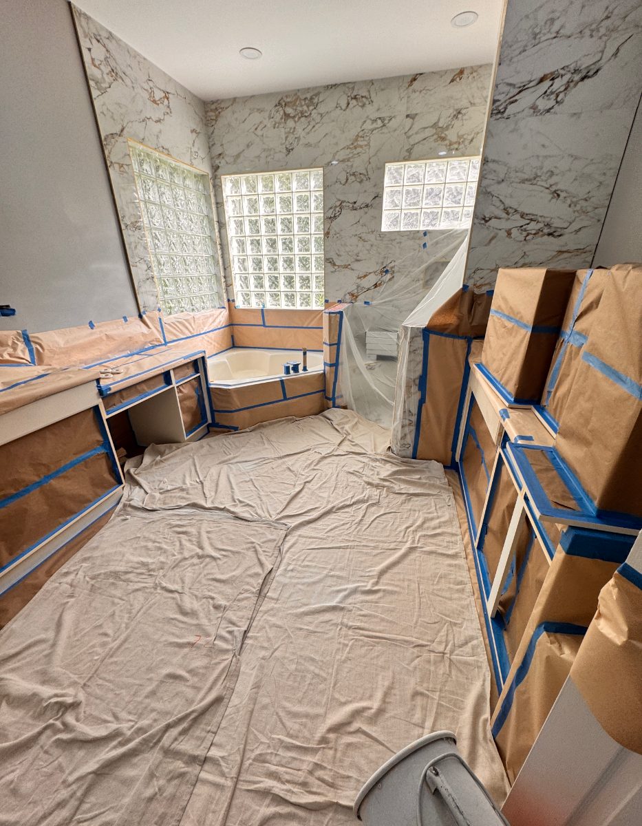 The same bathroom fully masked in paper, plastic, and drop cloths before spraying