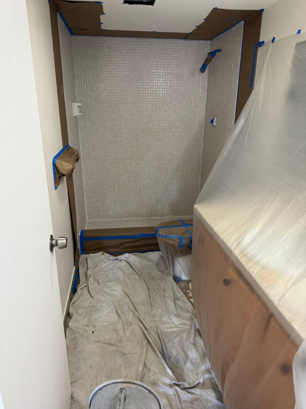 A mosaic-tile shower stall masked and papered before spraying