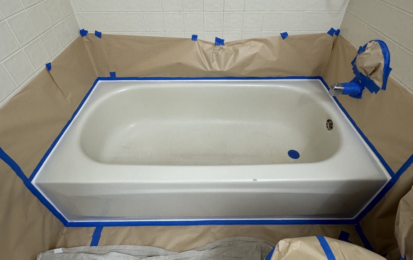 The same bathtub taped off and surrounded with masking paper, ready for spraying